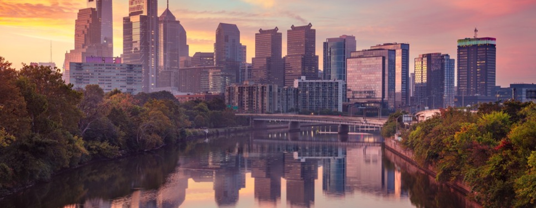 Philadelphia skyline reflecting on Schuylkill River at sunset with pink sky