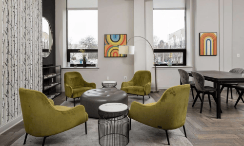 Resident lounge with green chairs and dining area at The Pepper Building